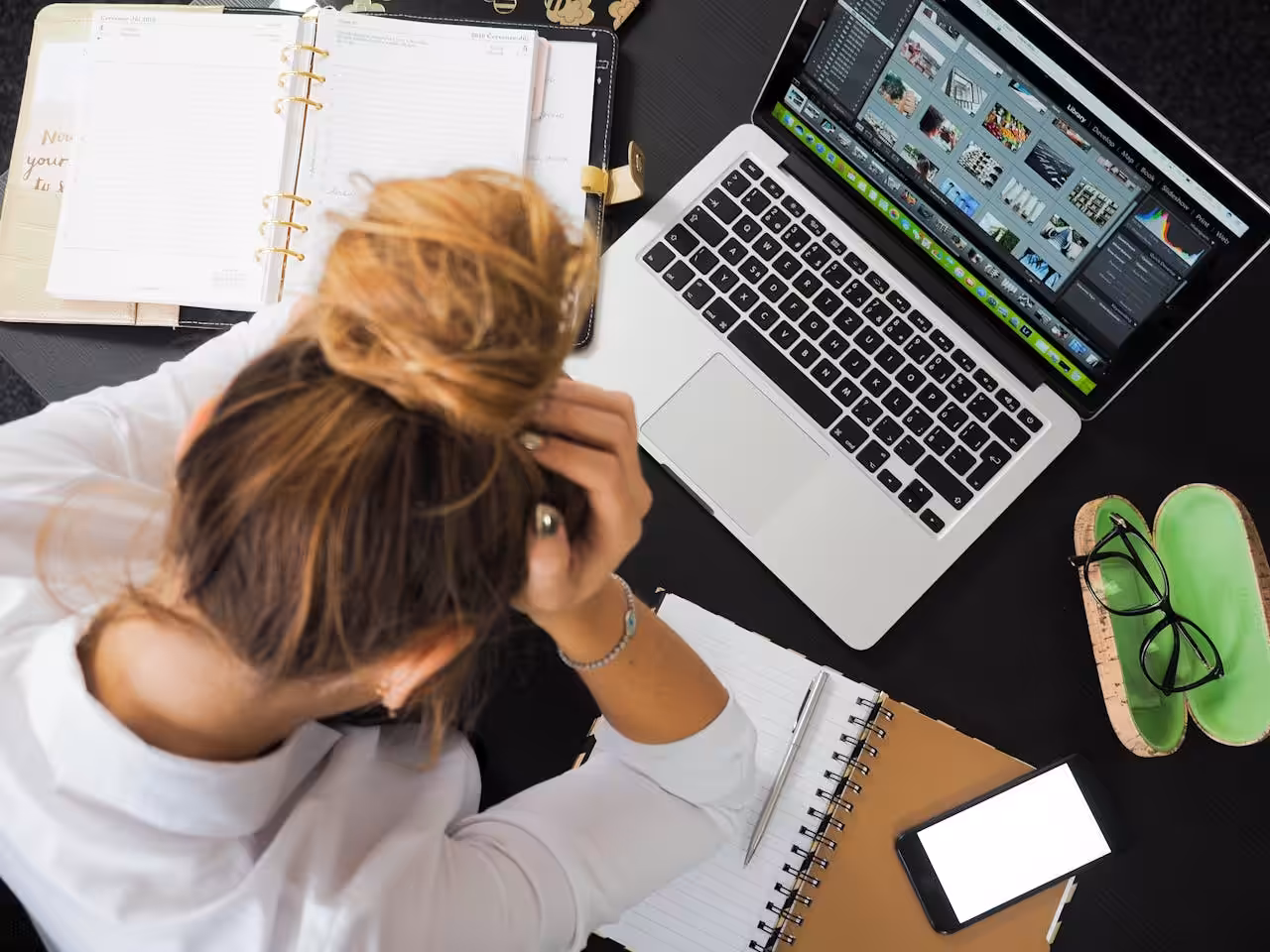 Picture of a woman sitting at a laptop with her head in her hands – WinuSoft | Web Hosting and Maintenance for WordPress Websites